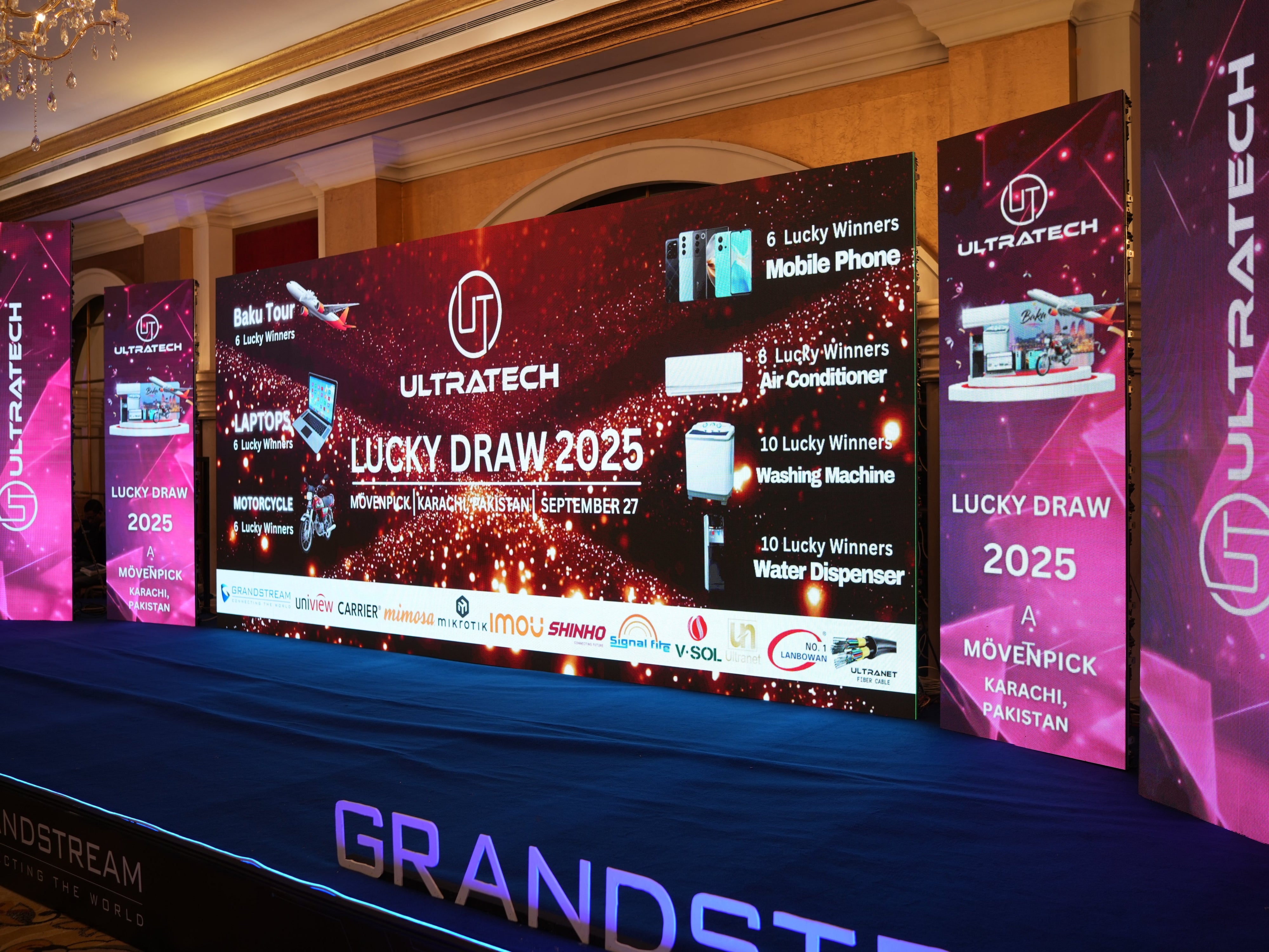 ULTRATECH Lucky Draw 2025 event display with multiple screens and branding.